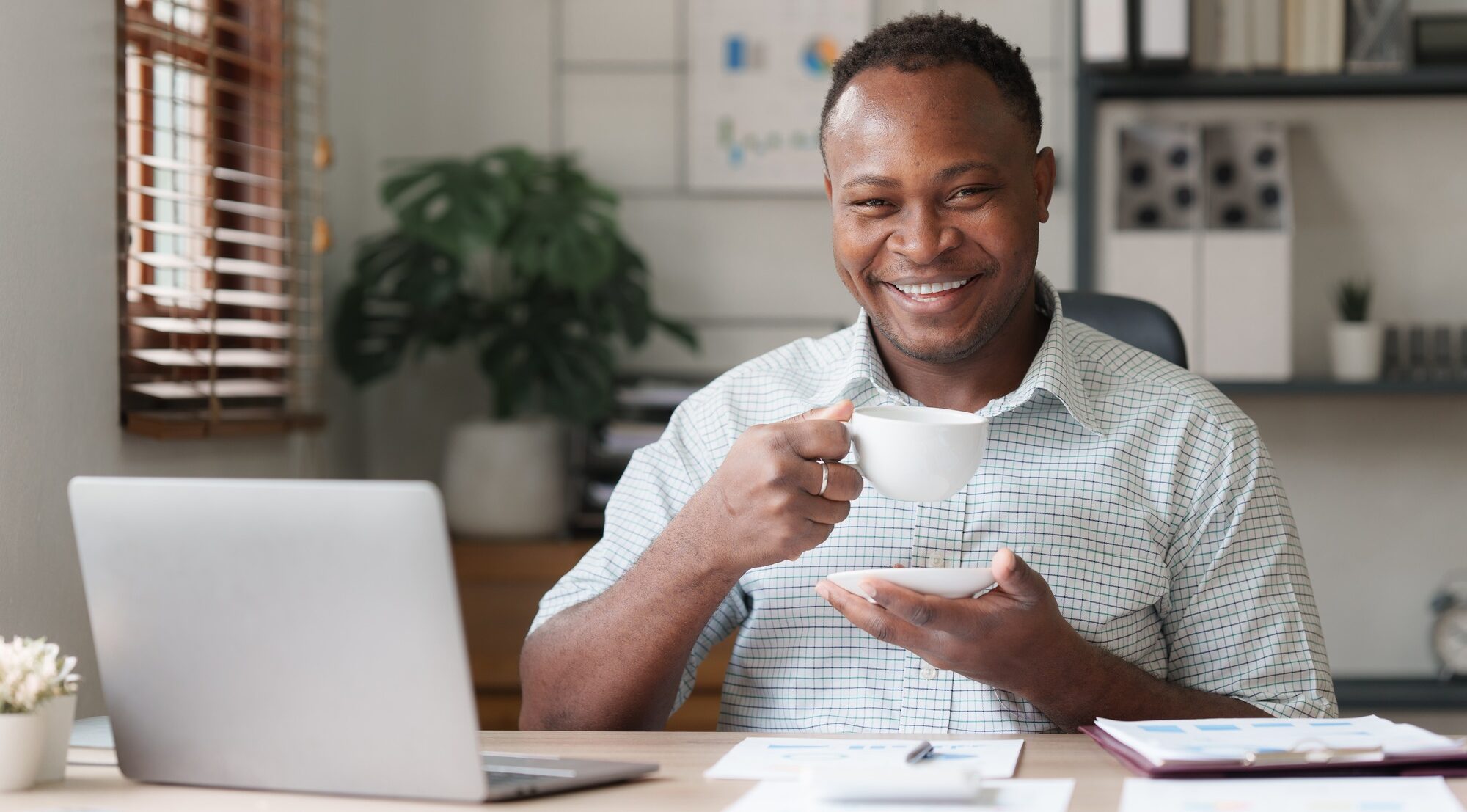 Smiling african business relaxing after analysis and research by laptop computer